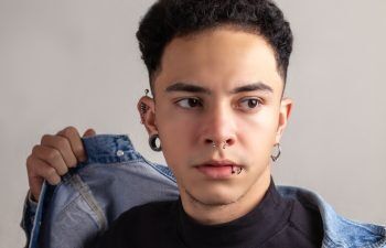 Model Young man with piercings, with curly hair and confident pose wearing a denim jacket