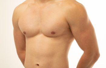 Young sportsman with athletic body posing in studio on isolated background. Smooth body after shaving. Firm torso after fitness gym. men's health: gastrointestinal diseases, gynecomastia