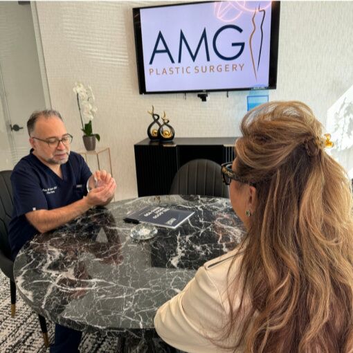 Surgeon consulting with a patient at a table in front of a wall-mounted screen