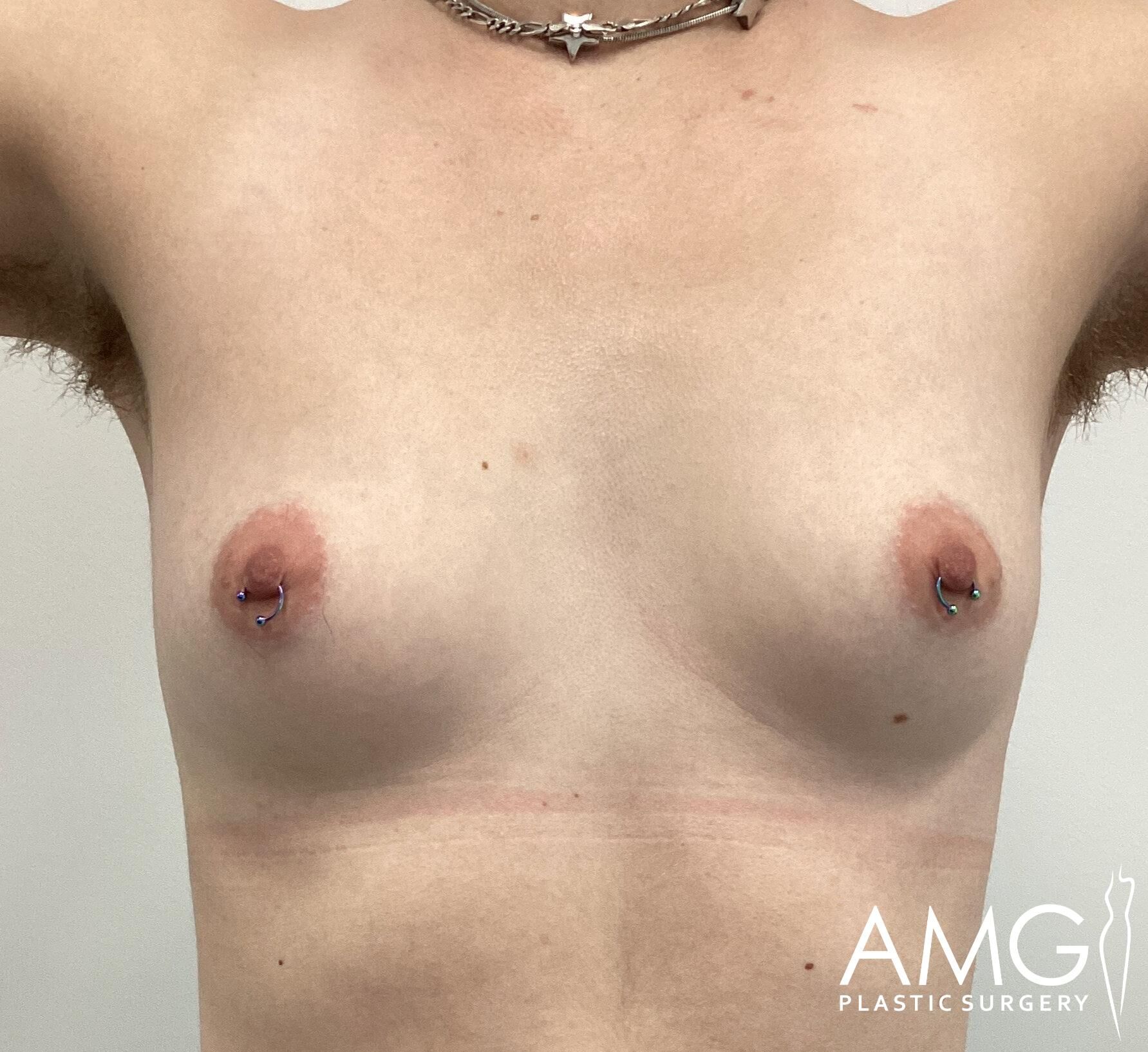 Person with pierced nipples and visible arm hair stands against a plain background. The logo 