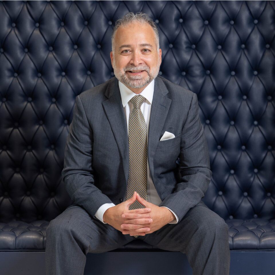 Surgeon in a suit seated on a tufted navy leather sofa